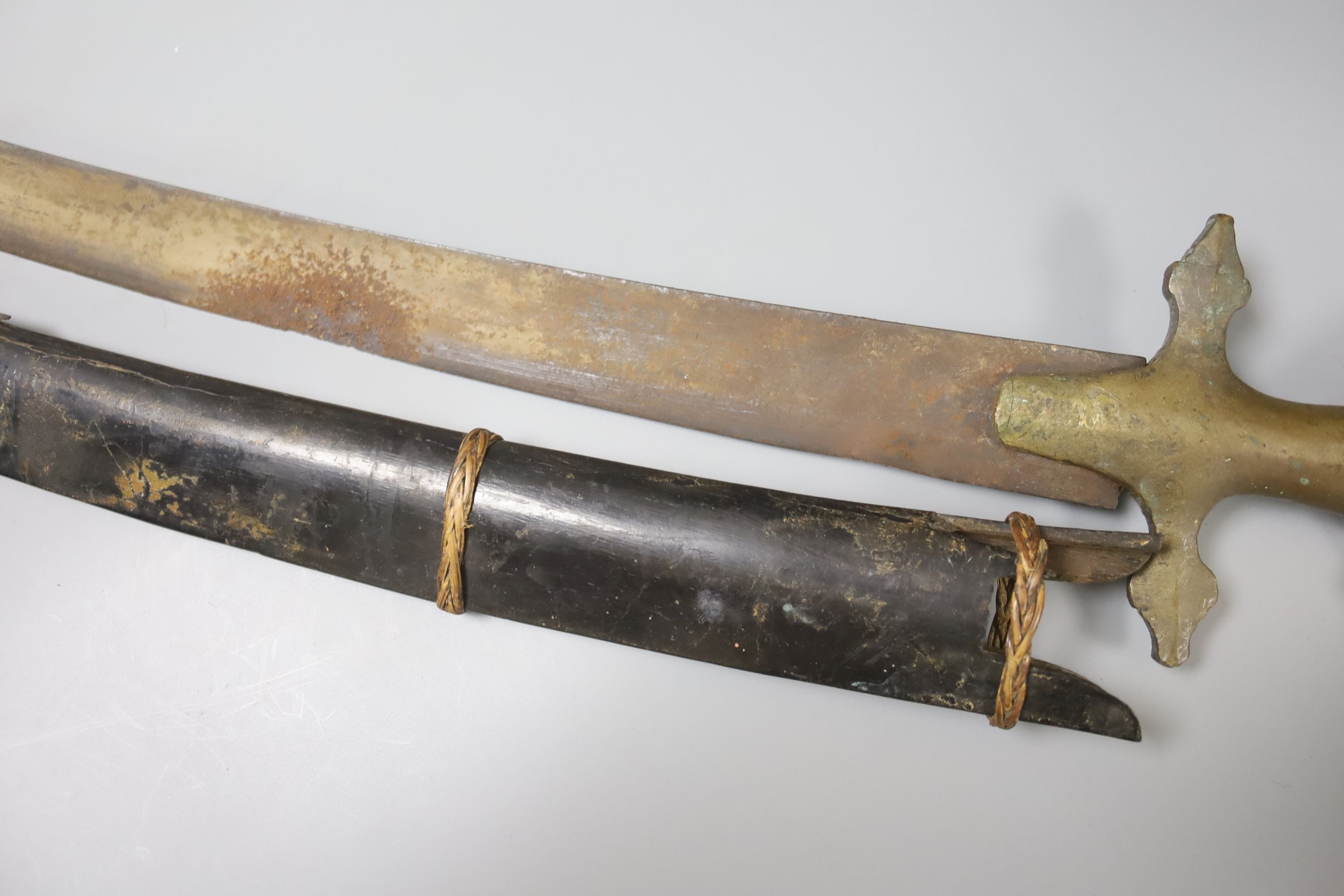 An Indonesian sword with brass handle, 19th century, blade stamped WARE Wd. CAST, in its ebony scabbard (damaged), blade 67cms